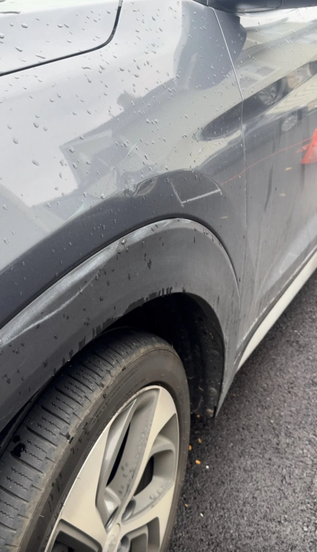 Gray SUV fender covered in dirt and water spots before the wash